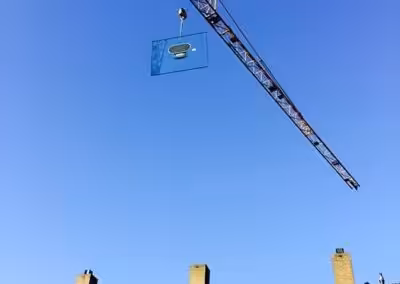 Grote isolatieruit met behulp van een torenkraan over de woning gehesen.