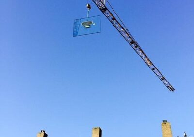 Grote isolatieruit met behulp van een torenkraan over de woning gehesen.